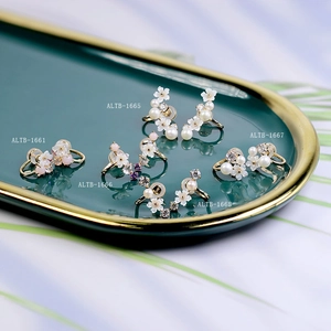 Detailed flat lay of shell flower ear clips and zircons on a luxury green tray