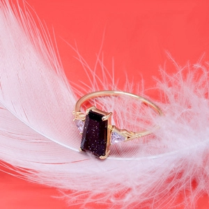 Macro d'une bague en pierre de soleil bleue et zircons posée sur une plume blanche