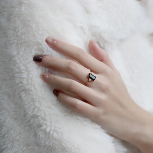 Détail d'une bague vintage avec pierre noire et anneau doré sur fond de fourrure blanche
