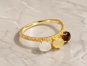 Detalle de anillo S925 dorado con texturas de vid y tres piedras de cristal de colores