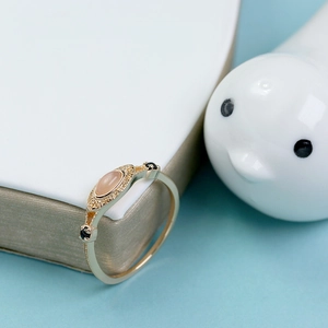 Primer plano de un anillo retro dorado con piedra de luna naranja y detalles calados finos