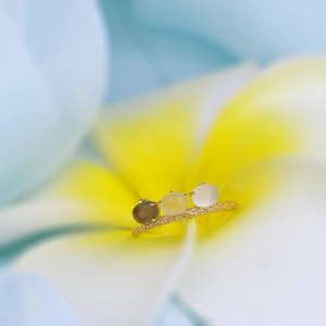 Detalle de anillo de plata 925 bañado en oro con tres gemas ovaladas sobre una flor