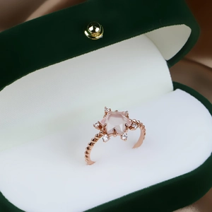 Detailansicht eines roségoldenen Rings mit sternförmigem rosa Edelstein im Etui