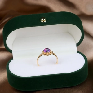 Detail of a 925 silver gold-plated ring with purple zircon in a green velvet box