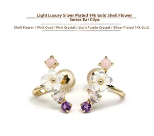 Macro detail of 925 silver gold plated ear cuffs with shell flowers and pink crystals