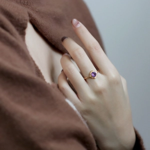 Detailed macro of vintage gold ring featuring a purple zircon and twisted rope band