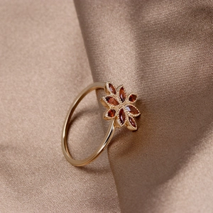 Detail of vintage 925 silver gold-plated ring with garnet flower petals and silk backdrop