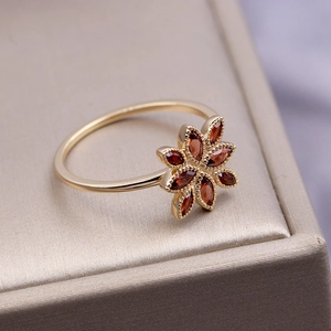 Detail of flower shaped gold ring with marquise cut garnet stones on a jewelry box