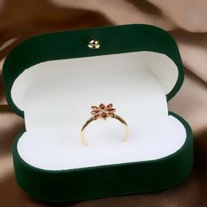 Detail of flower-shaped ring with red pomegranate stones in a green velvet jewelry box