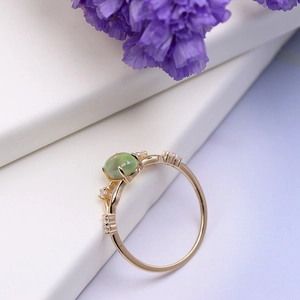 Macro detail of natural green prehnite stone and zircon accents on a gold plated ring