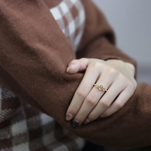 Detailed view of an oval natural prehnite ring in rose gold on a model's finger