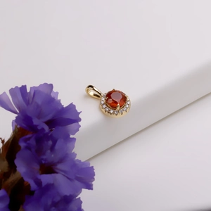 Macro view of a gold pendant featuring an orange garnet center and zircon halo detail