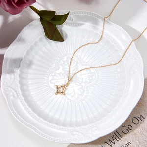 Macro shot of gold-plated silver pendant with white crystal inlay on vintage ceramic tray