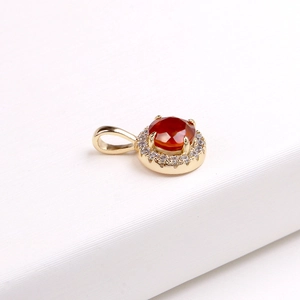Macro shot of gold pendant featuring a round garnet main stone with CZ halo setting