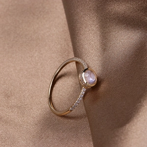 Close-up of gold-plated silver ring with round pink quartz stone and pavé zircon settings