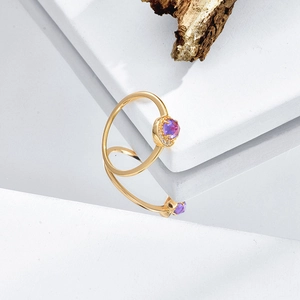 Spiralgoldring mit lila Edelstein-Mittelstück auf minimalistischem Display