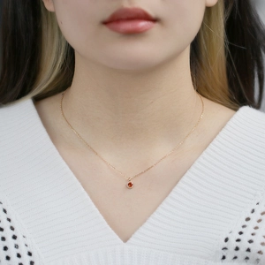 Close-up of a s925 silver halo pendant with orange garnet on a woman's collarbone