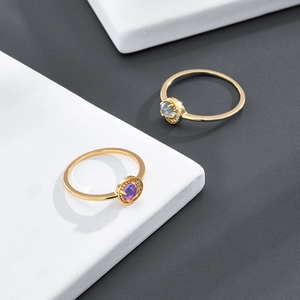 Detail von zwei goldenen Ringen mit rotem Edelstein und grauem Marmorstein auf weißem Tablett