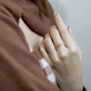 Close-up of a rose gold ring featuring a round pink quartz stone and micro-pave diamonds