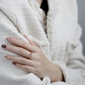 Nahaufnahme eines eleganten Goldrings mit rundem rosa Edelstein am Finger