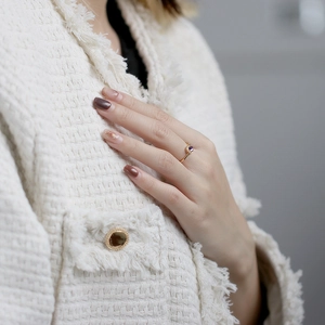 Detailansicht eines schmalen Goldrings mit lila Edelstein am Finger eines Models