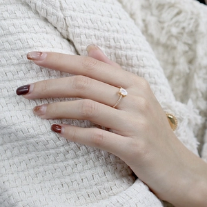 Macro shot of rose gold ring featuring moonstone and pave cubic zirconia on finger