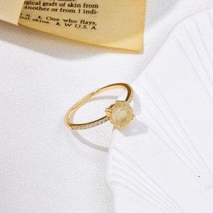 Vue macro d'une bague dorée vintage avec pierre jaune et détails en zircons blancs sertis