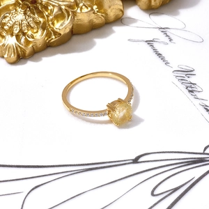 Détail d'une bague dorée avec quartz rutilé jaune et zircons scintillants de près