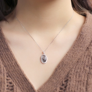 Makroaufnahme eines ovalen schwarzen Rutilquarz-Anhängers mit Diamanten an einer Silberkette