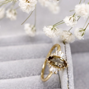 Primer plano de un anillo de cuarzo ahumado con talla marquesa y detalles de circón