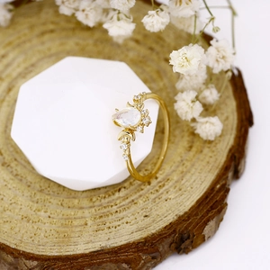 Macro detail of gold teardrop opal ring with diamond accents on a natural wood display