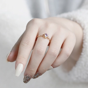 Detailed view of rose gold pear-shaped opal ring with moon accents on female hand