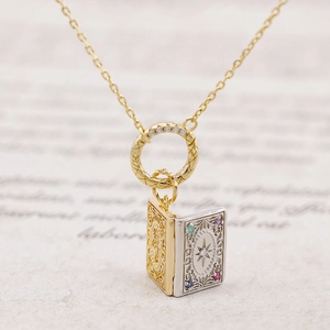 Macro detail of antique style book pendant with gold plating and colored gemstones