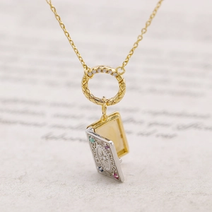 Macro shot of vintage silver book pendant with colorful gemstones and sunburst engraving