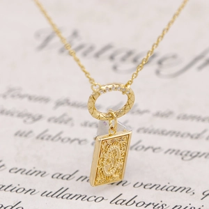 Macro detail of vintage gold book pendant with intricate floral relief and diamonds