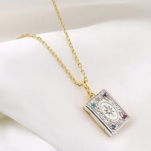 Detail of vintage book locket with vine engraving and colorful gemstones on white silk