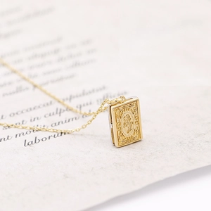 Macro detail of vintage golden book locket pendant with floral relief and fine O-chain