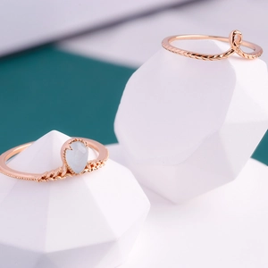 Detail van roségouden ringen met een peervormige aquamarijn en gestructureerde banden