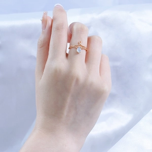 Detail van een roségouden V-vormige kroonring met druppelvormige blauwe edelsteen op zijde