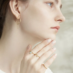 Detail van 925 zilver vergulde ringen met aquamarijn en gouden oorbellen op model