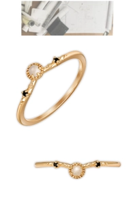 Detail van een V-vormige gouden ring met witte parel, zwarte edelstenen en vintage textuur