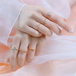 6-delige gouden ringenset met blauwe en paarse edelstenen aan de hand van model