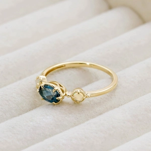 Détail d'une bague dorée vintage avec topaze bleue de Londres et opale blanche