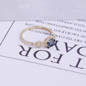 Gros plan sur bague en or avec topaze bleu de Londres et opale sur ruban