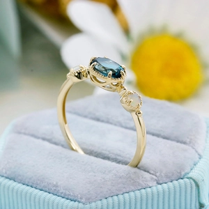 Vue macro d'une bague vintage en or avec topaze bleue et opales dans un écrin en velours