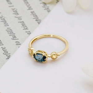 Détail macro de la bague en or avec topaze bleue de Londres et opales rondes serties griffes