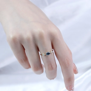 Gros plan d'une bague en or avec topaze bleue et opale portée au doigt