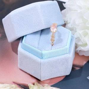 Detail of tear-shaped rose quartz ring with white zircons in a blue velvet box