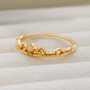 Nahaufnahme eines goldenen Kronenrings mit hohlem Design und Opalstein-Inlay