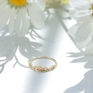 Makroaufnahme eines S925 Silber-Kronenrings mit Opal auf weißen Gänseblümchen